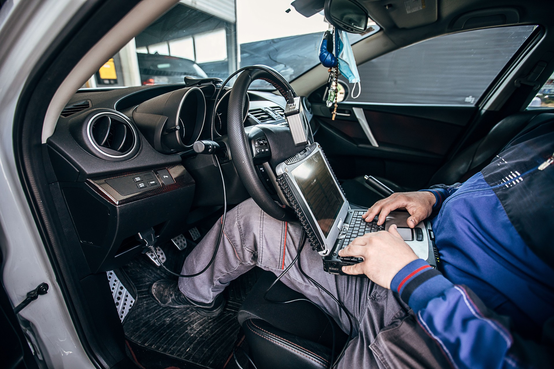 Car repairman using computer while testing new car's performance in a workshop